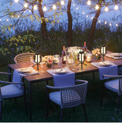 Outdoor dining setup with string lights and candles in a garden.